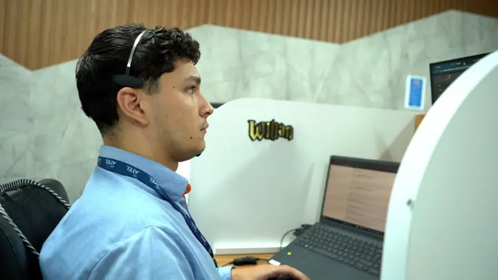 Atendente da Atel de uniforme azul com headset no computador